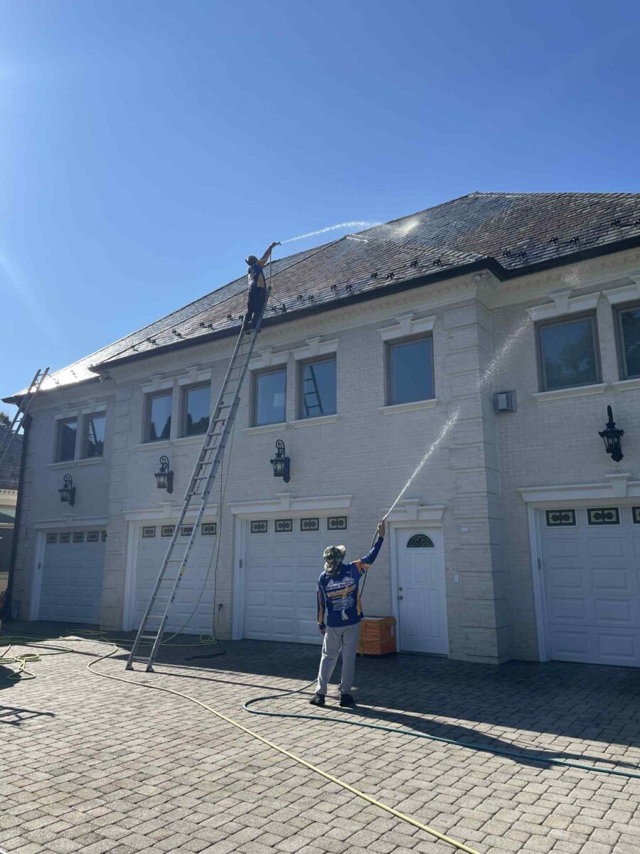three shine select employees pressure washing a multifamily building roof
